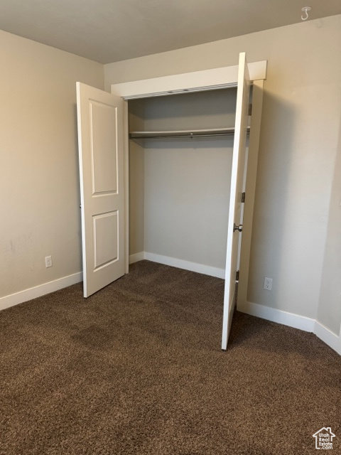 Unfurnished bedroom featuring a closet and dark colored carpet