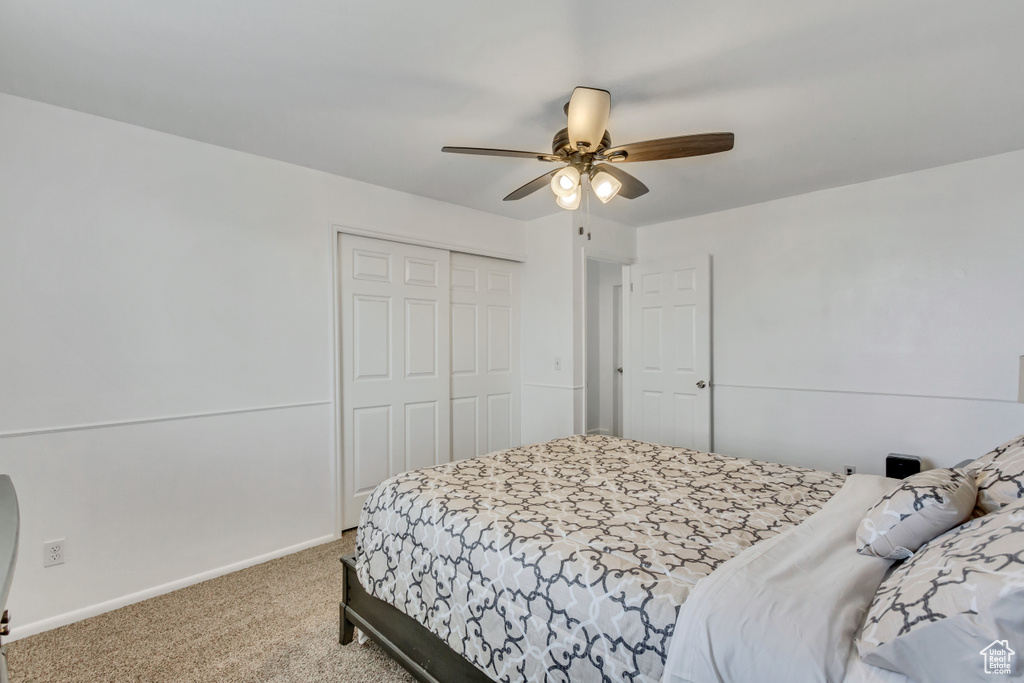 Bedroom with ceiling fan, a closet, and light carpet