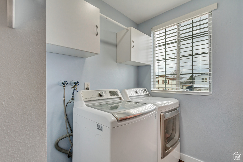 Clothes washing area featuring washer and dryer and cabinets