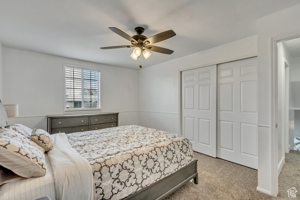 Carpeted bedroom featuring ceiling fan and a closet