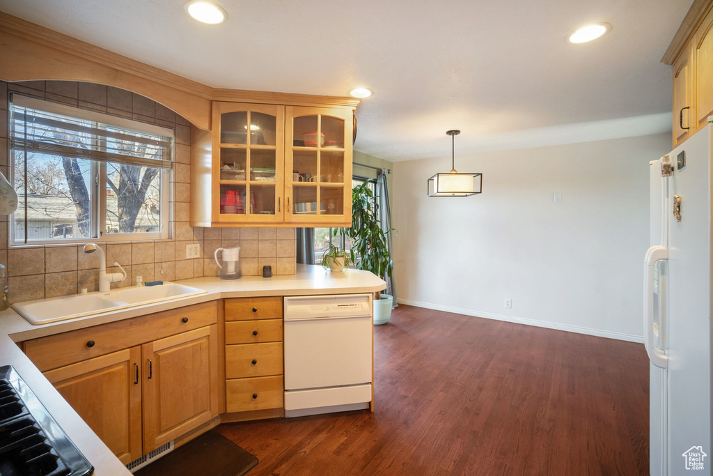 Kitchen featuring backsplash, white appliances, dark hardwood / wood-style floors, and pendant lighting