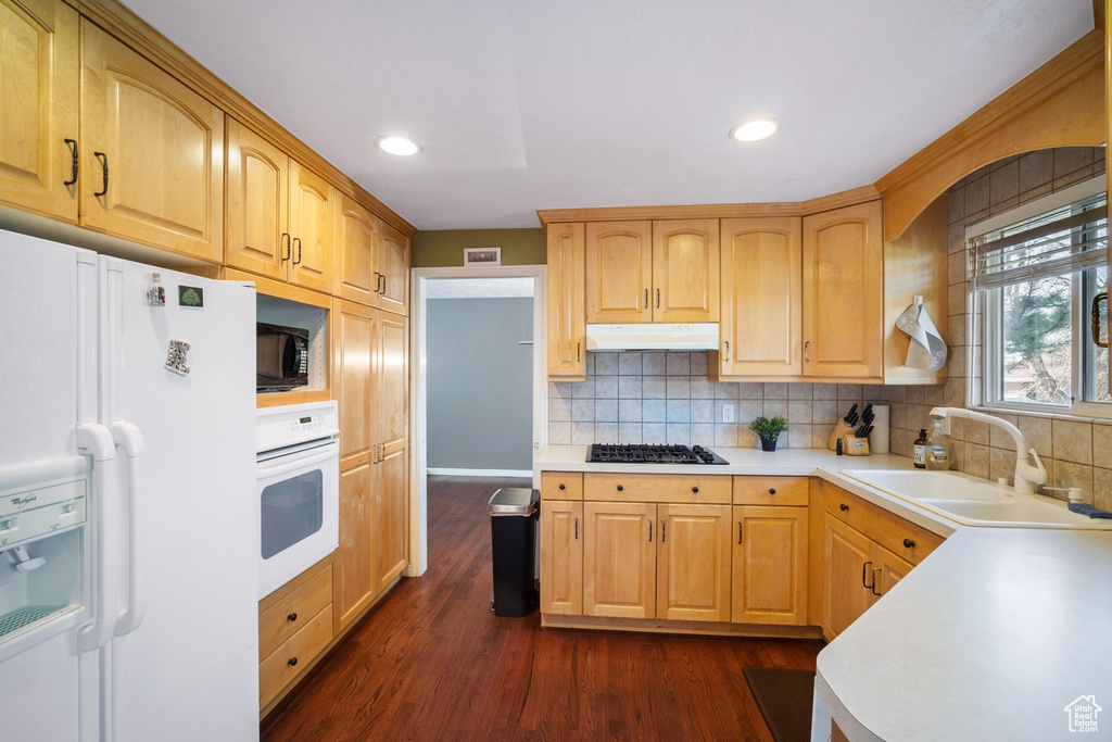 Kitchen with tasteful backsplash, white appliances, dark hardwood / wood-style flooring, sink, and light brown cabinets