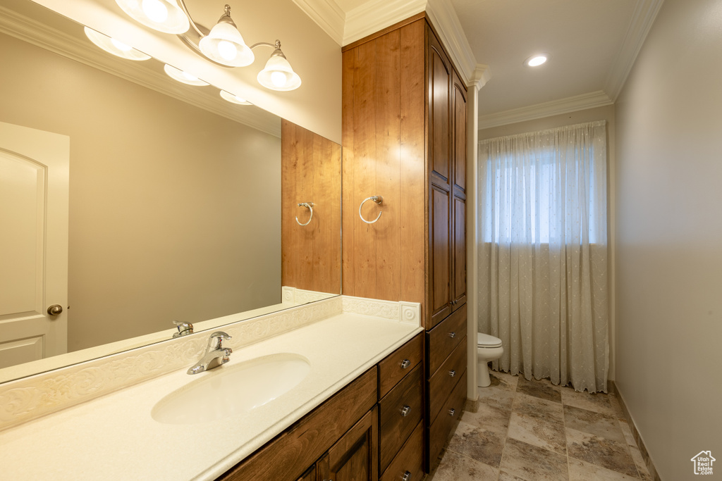 Bathroom with a chandelier, toilet, vanity, ornamental molding, and tile floors