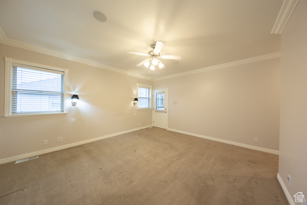 Empty room with light colored carpet, ceiling fan, and crown molding