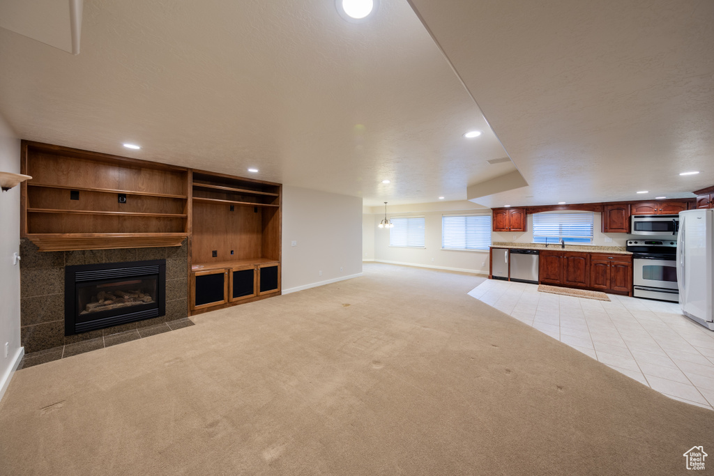 Unfurnished living room with light colored carpet, sink, and a fireplace