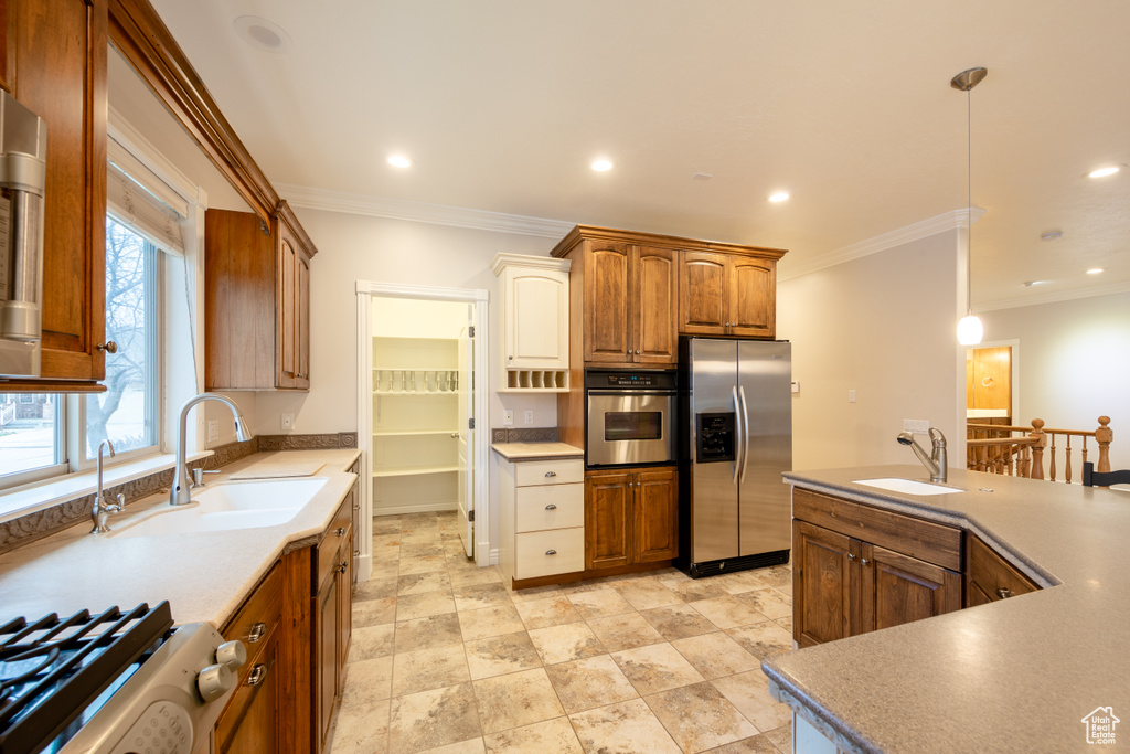 Kitchen featuring pendant lighting, light tile floors, sink, crown molding, and stainless steel appliances