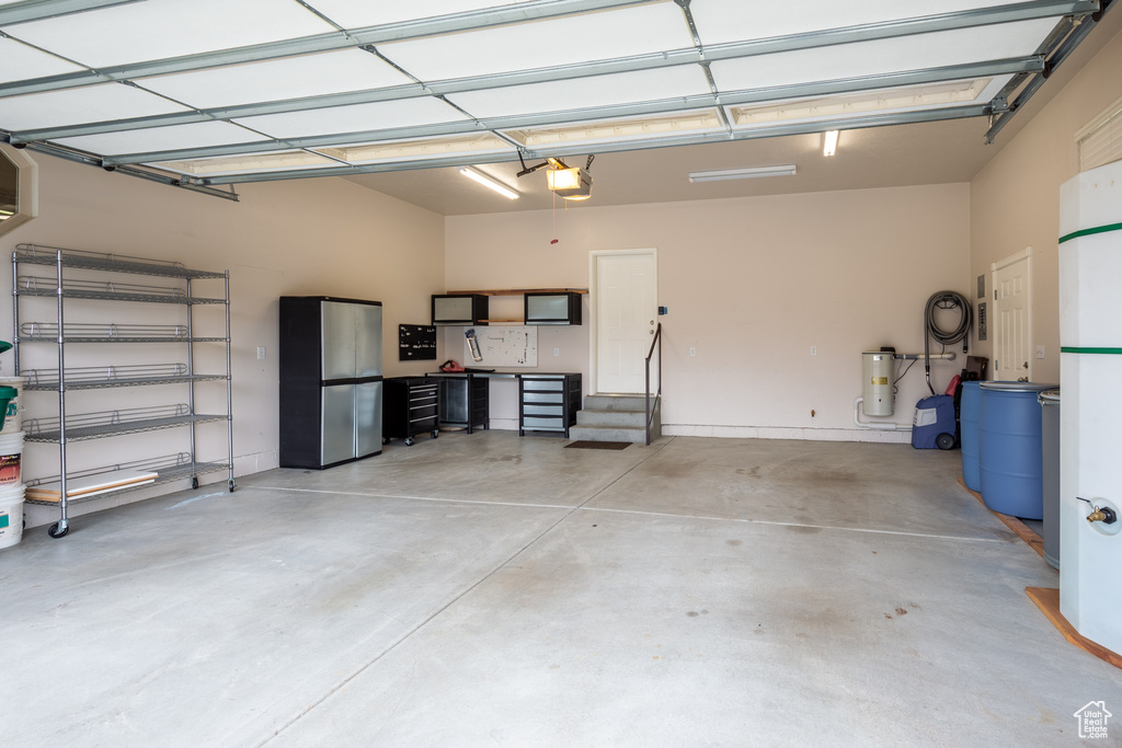 Garage with stainless steel refrigerator and a garage door opener