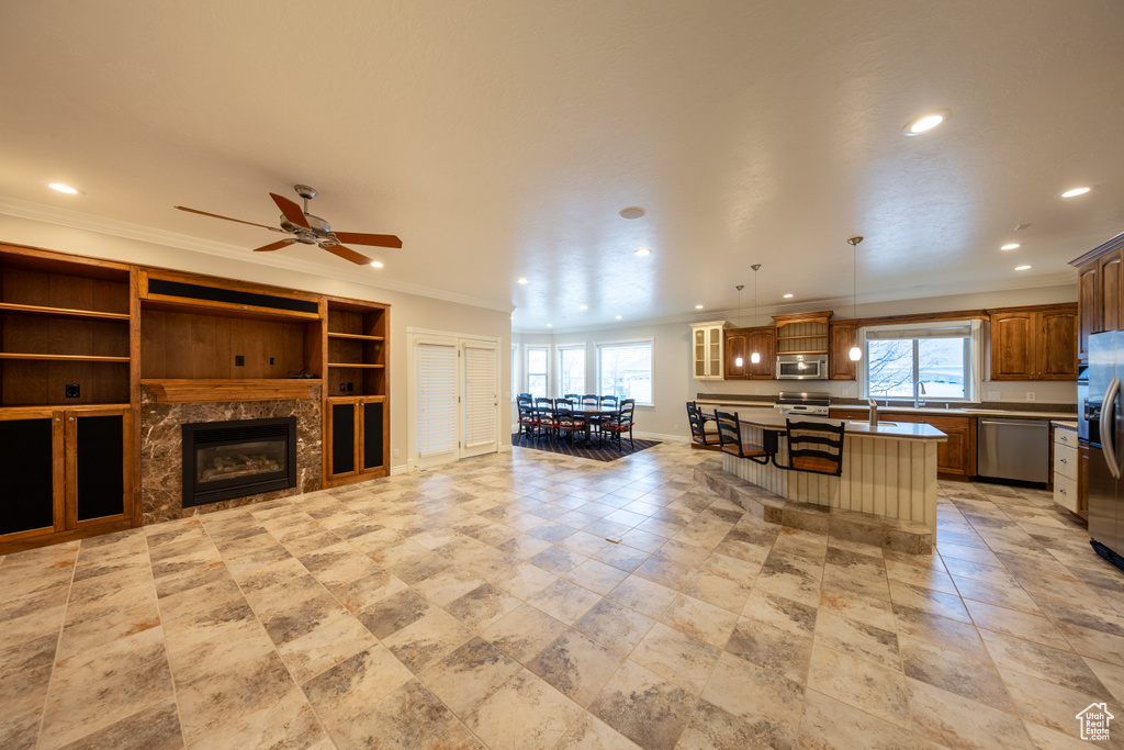 Kitchen featuring a kitchen island, ceiling fan, a breakfast bar, a premium fireplace, and hanging light fixtures
