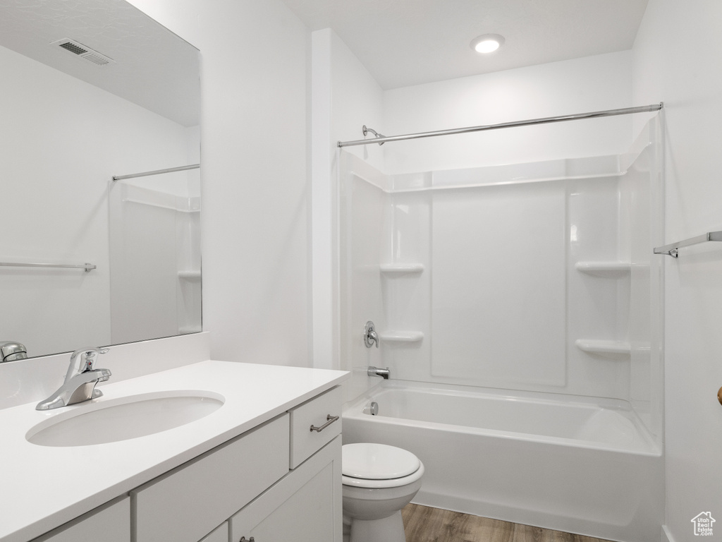 Full bathroom with vanity, hardwood / wood-style floors,  shower combination, and toilet