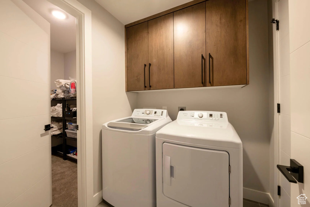 Clothes washing area with cabinets, washing machine and dryer, and carpet