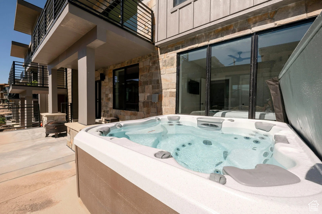 View of swimming pool with a hot tub and a patio