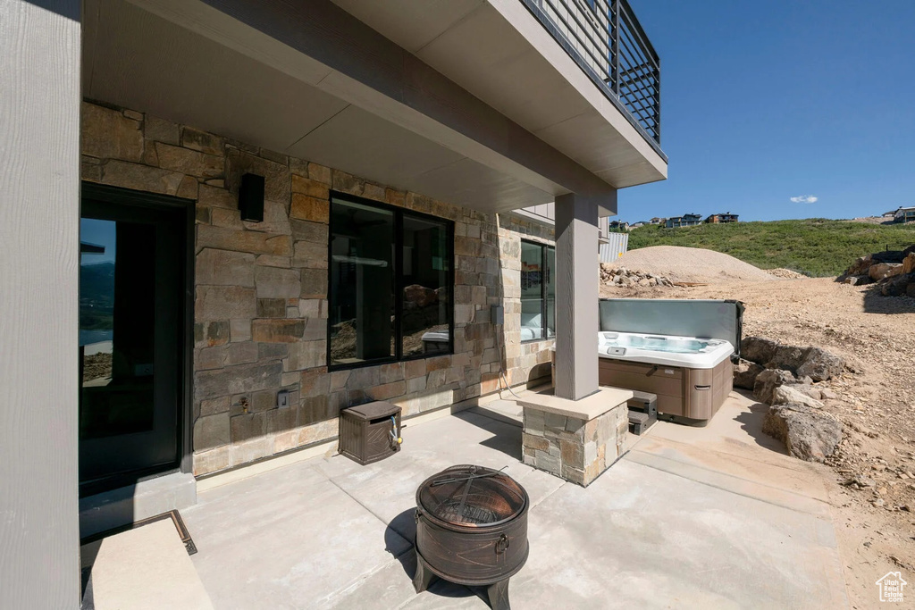 View of patio / terrace featuring a balcony, a fire pit, and a hot tub