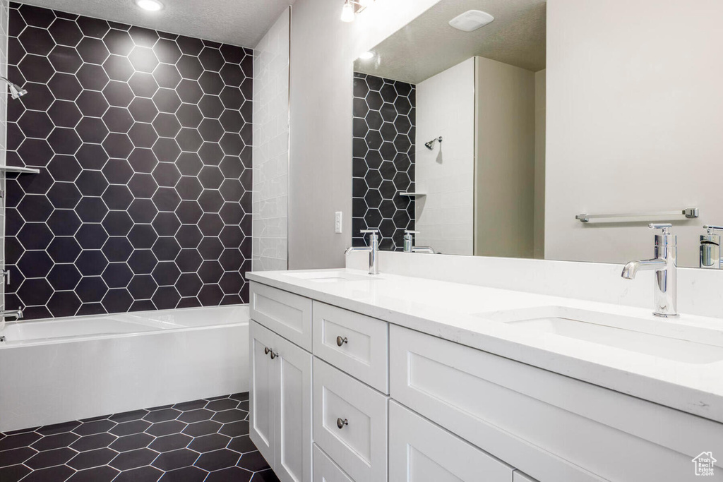 Bathroom with dual vanity, a textured ceiling, and tile floors