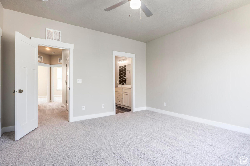 Unfurnished bedroom featuring ceiling fan, light colored carpet, and ensuite bath