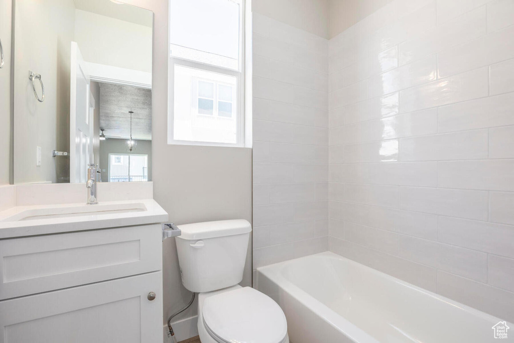 Full bathroom with toilet, vanity with extensive cabinet space, and tiled shower / bath combo