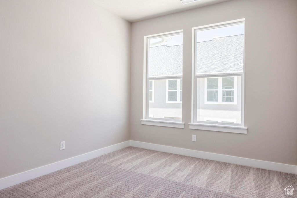 Empty room featuring light colored carpet and plenty of natural light