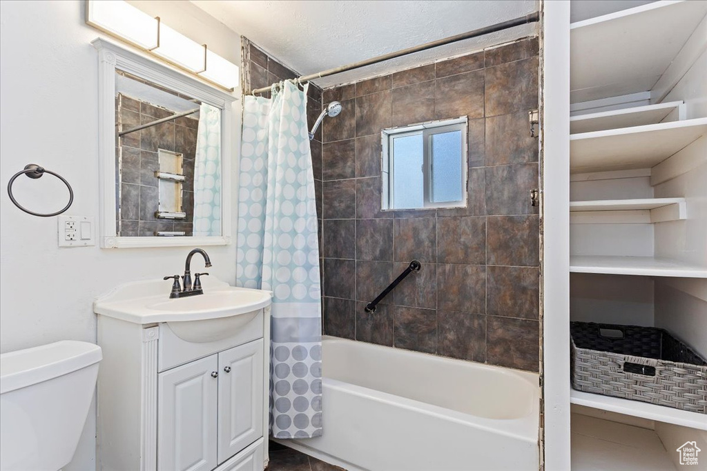 Full bathroom with tile floors, shower / bath combination with curtain, toilet, and vanity