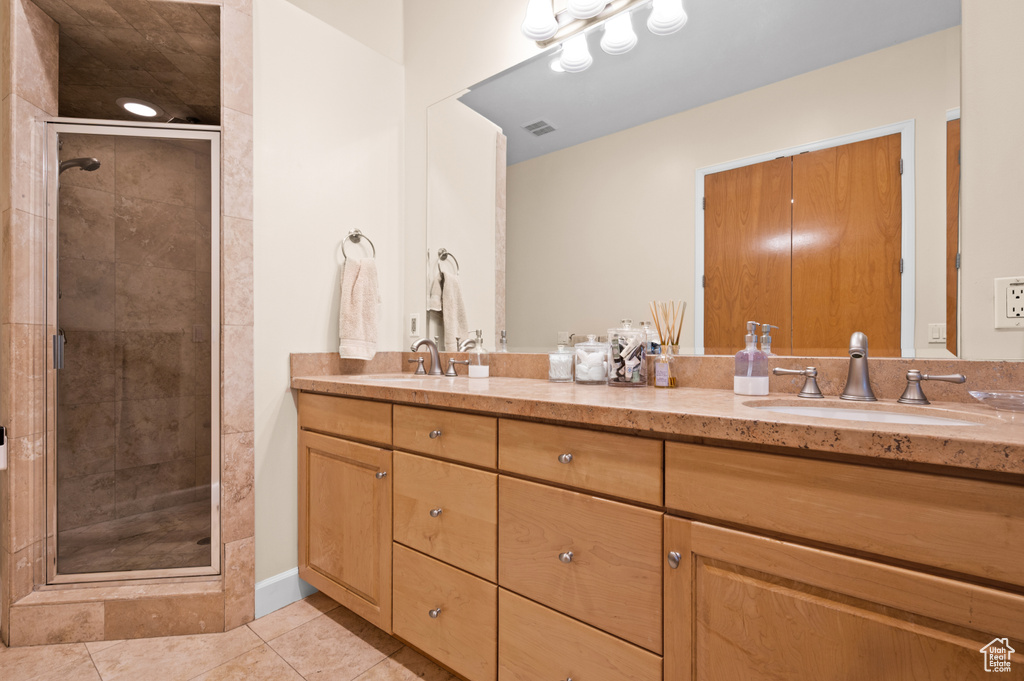 Bathroom featuring oversized vanity, double sink, tile flooring, and walk in shower