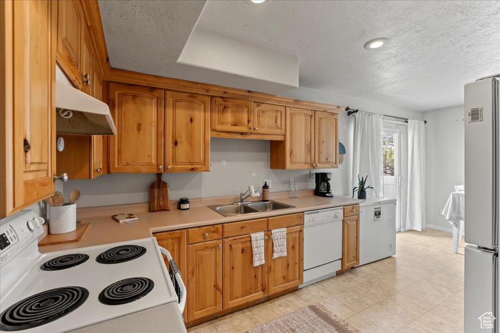 Kitchen featuring range, wall chimney exhaust hood, stainless steel fridge, dishwasher, and sink