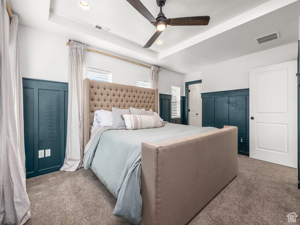 Bedroom featuring ceiling fan, dark carpet, and a raised ceiling