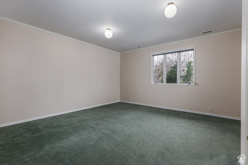 Spare room featuring dark colored carpet and ornamental molding