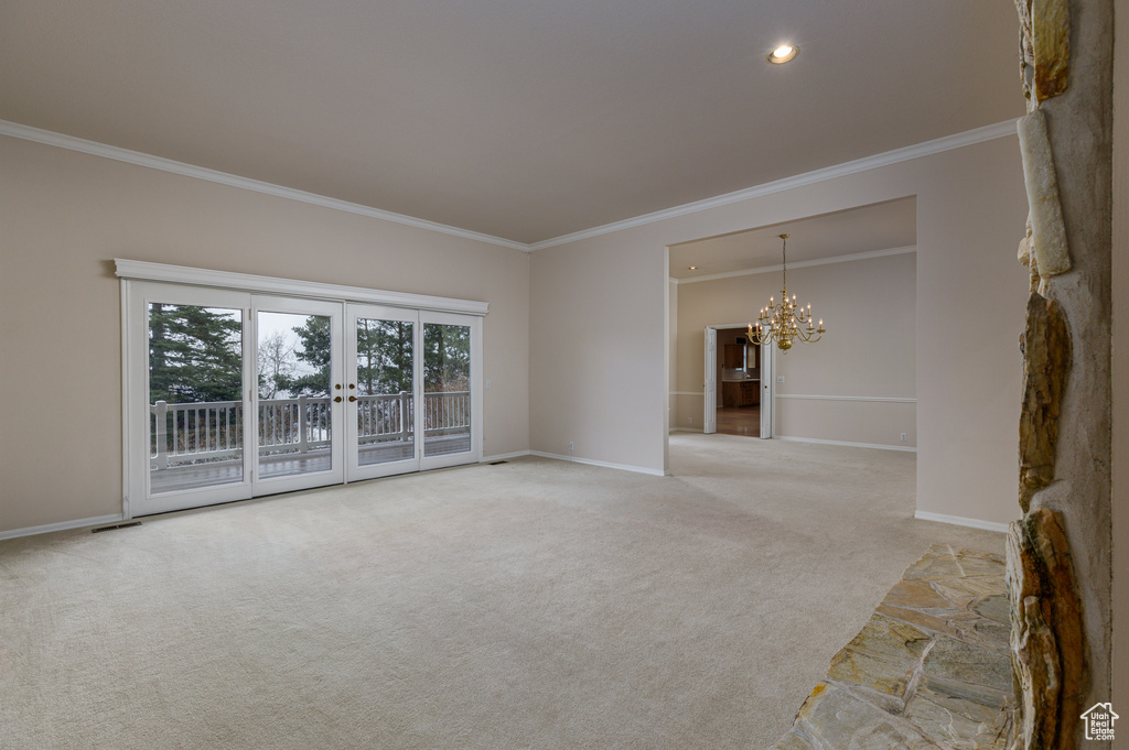 Unfurnished room with crown molding, french doors, an inviting chandelier, and light colored carpet