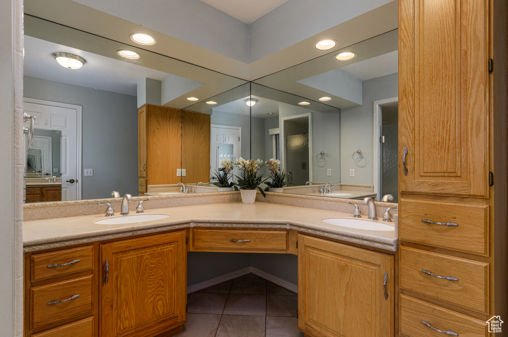 Bathroom featuring vanity with extensive cabinet space, dual sinks, and tile floors