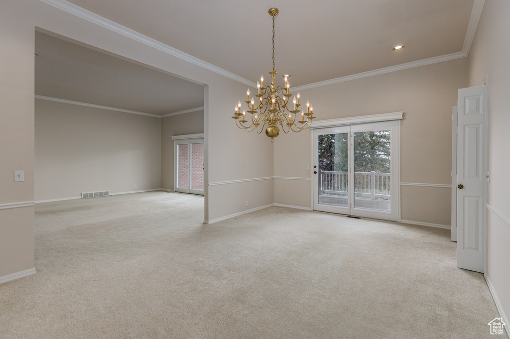Carpeted empty room featuring crown molding and an inviting chandelier