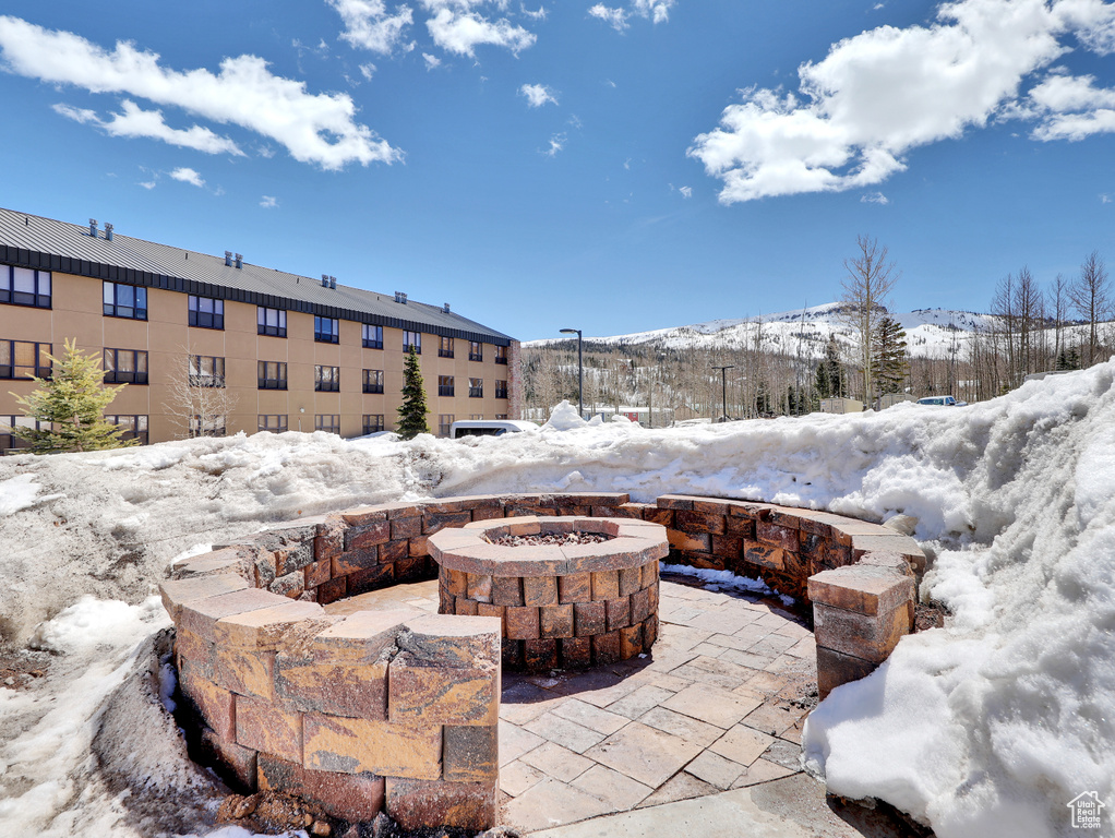 Snow covered patio with a mountain view and an outdoor fire pit