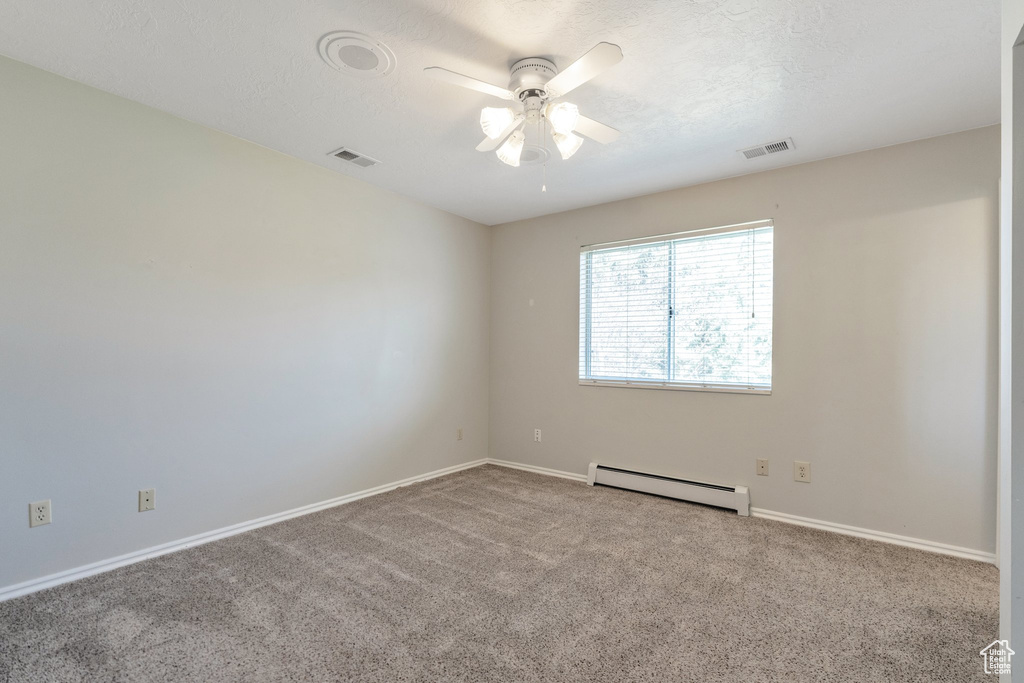 Spare room with ceiling fan, a baseboard radiator, and light colored carpet