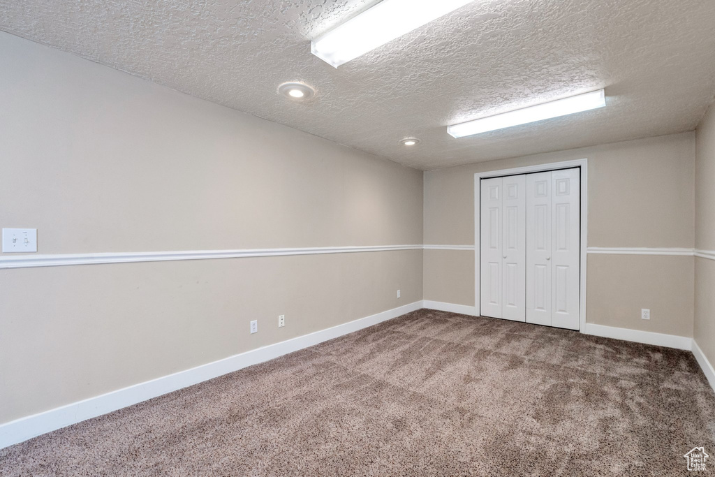 Interior space with a closet, dark colored carpet, and a textured ceiling