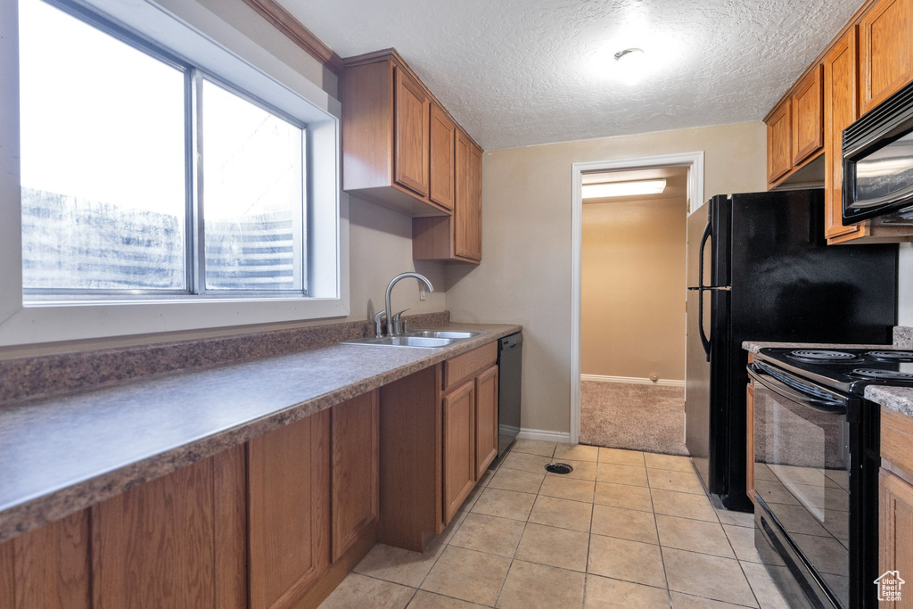Kitchen with sink, light tile floors, black appliances, and plenty of natural light