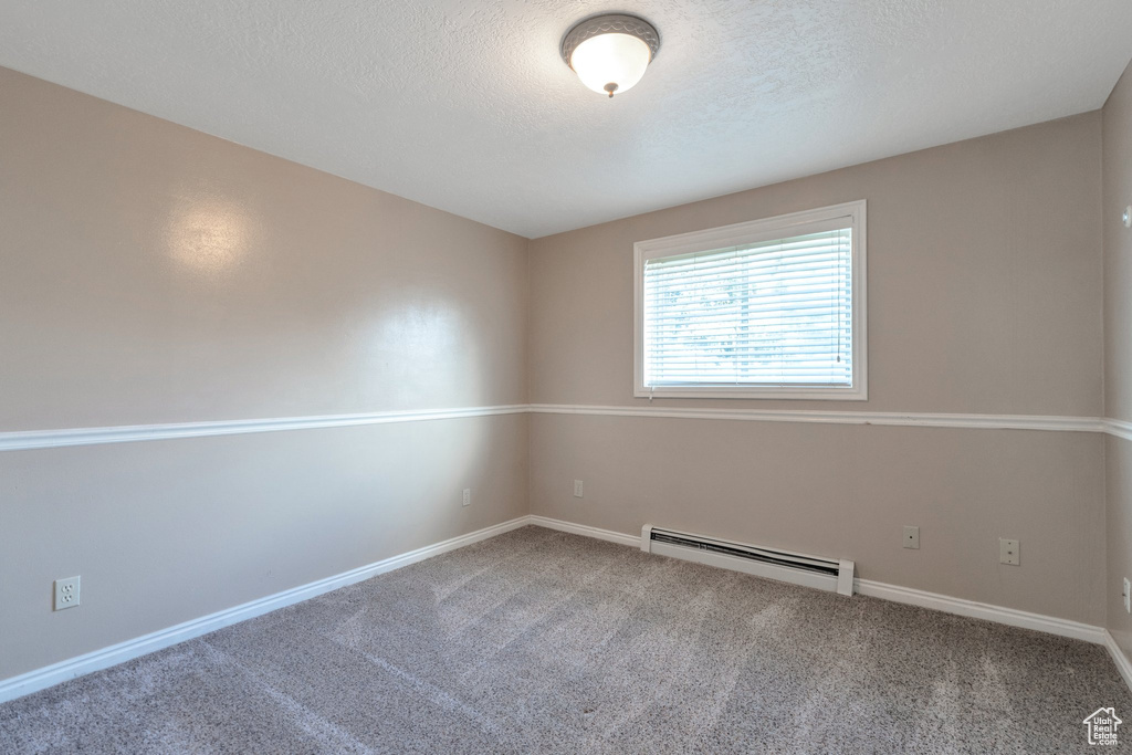 Empty room with baseboard heating, carpet floors, and a textured ceiling
