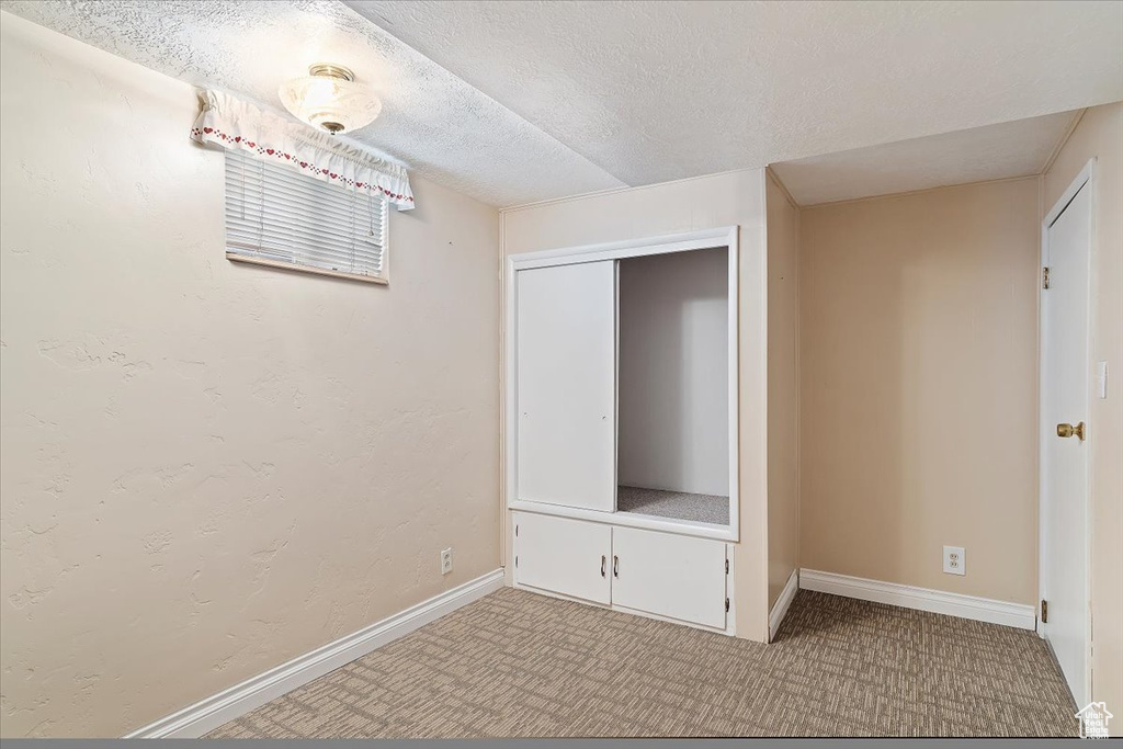 Unfurnished bedroom featuring a textured ceiling, light colored carpet, and a closet