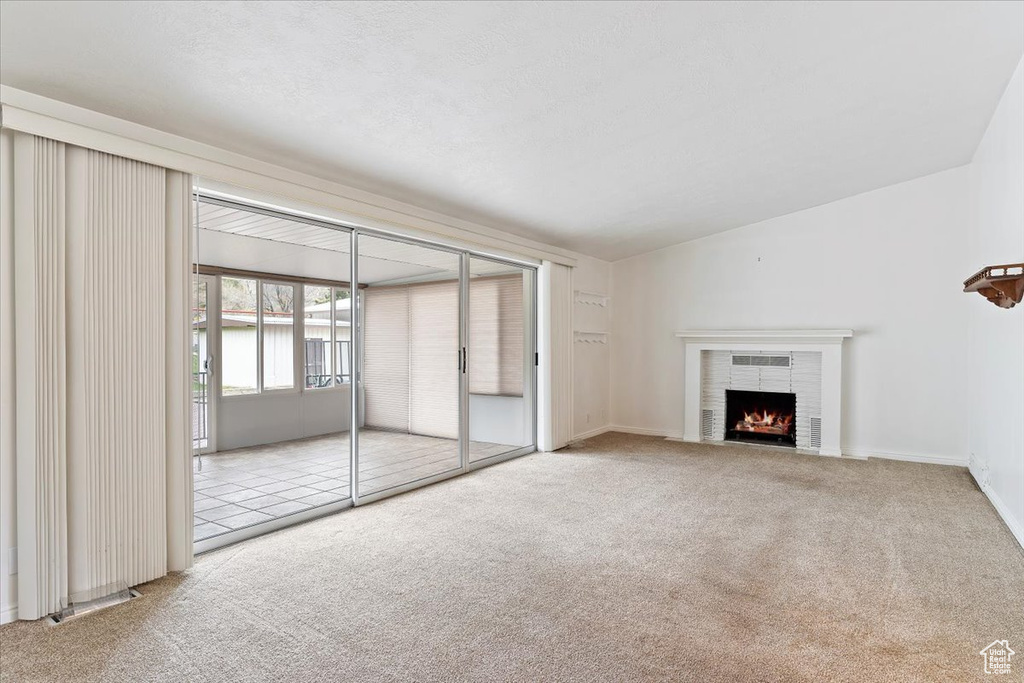 Unfurnished living room with light carpet and a brick fireplace