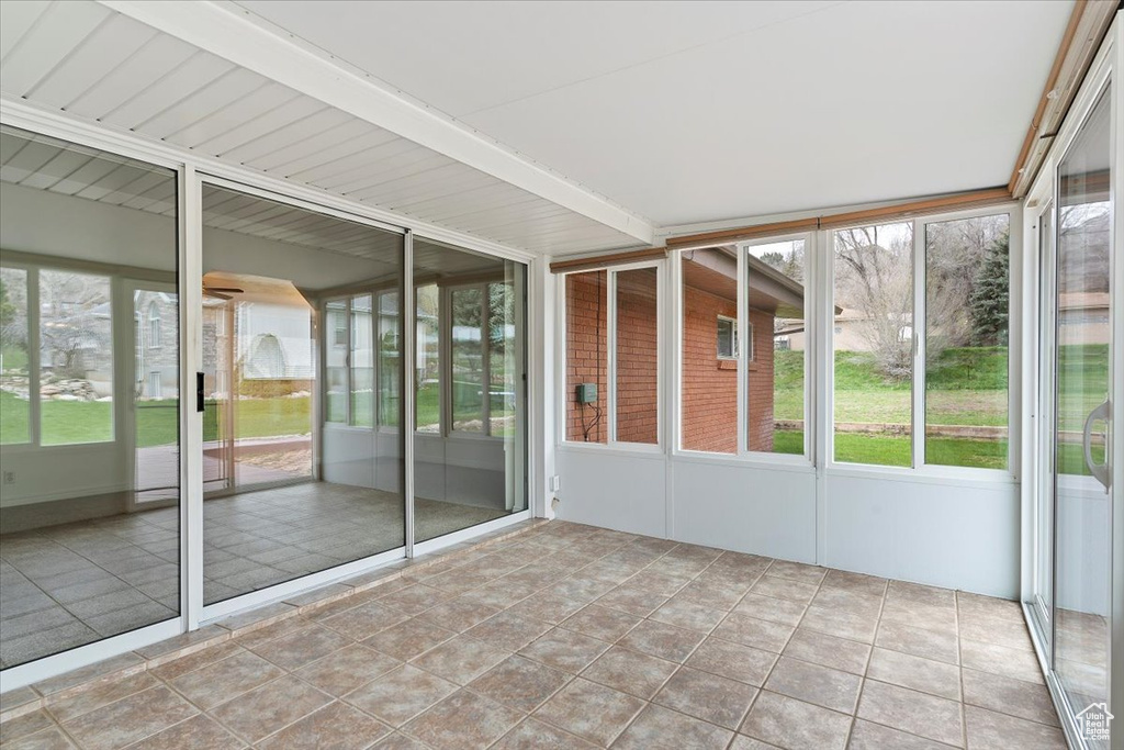Unfurnished sunroom featuring beam ceiling