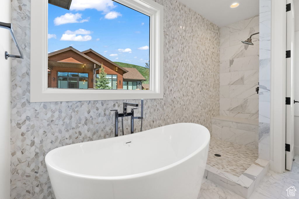Bathroom featuring shower with separate bathtub and tile flooring