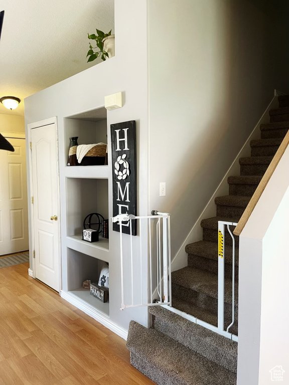 Stairway with built in features and light hardwood / wood-style floors