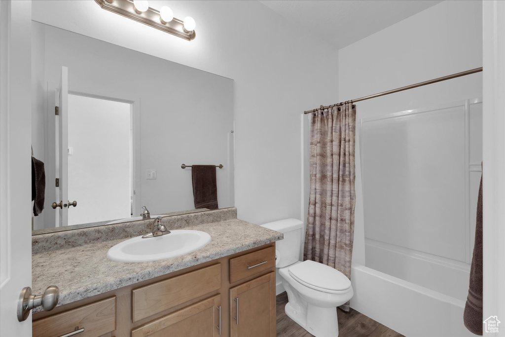 Full bathroom featuring toilet, vanity, hardwood / wood-style flooring, and shower / tub combo with curtain