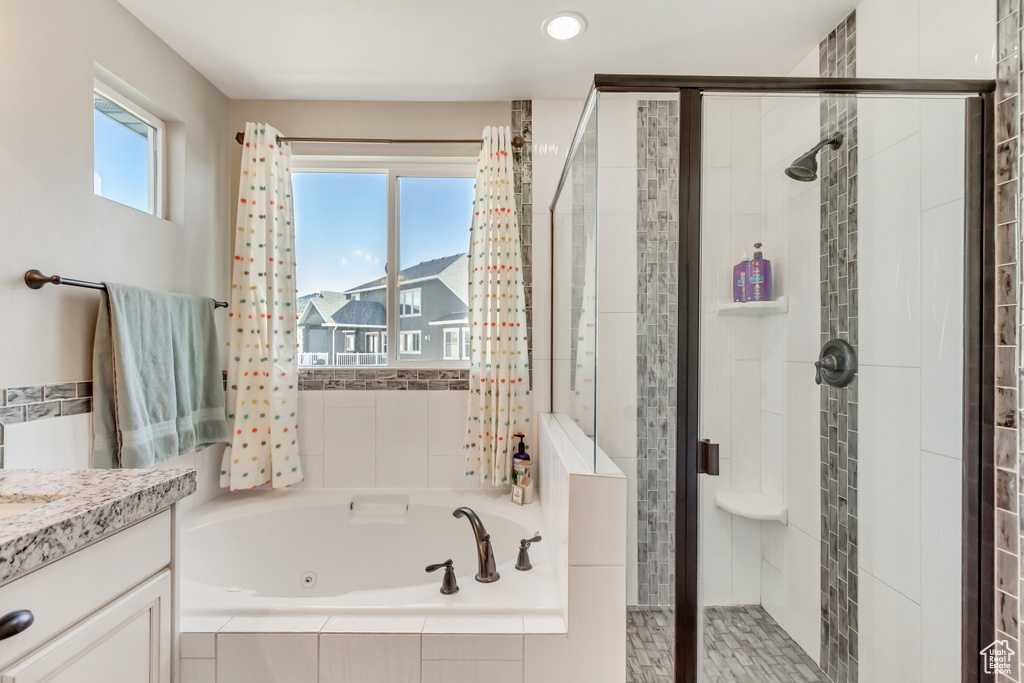 Bathroom with separate shower and tub, a wealth of natural light, and vanity