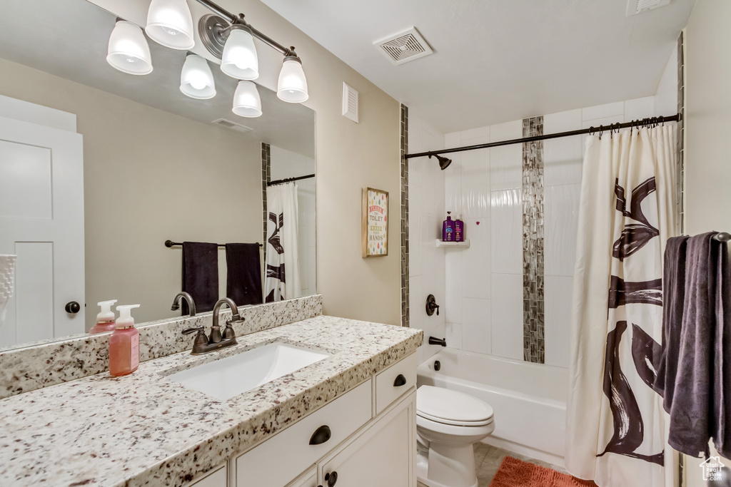 Full bathroom with shower / bath combination with curtain, tile flooring, vanity with extensive cabinet space, and toilet