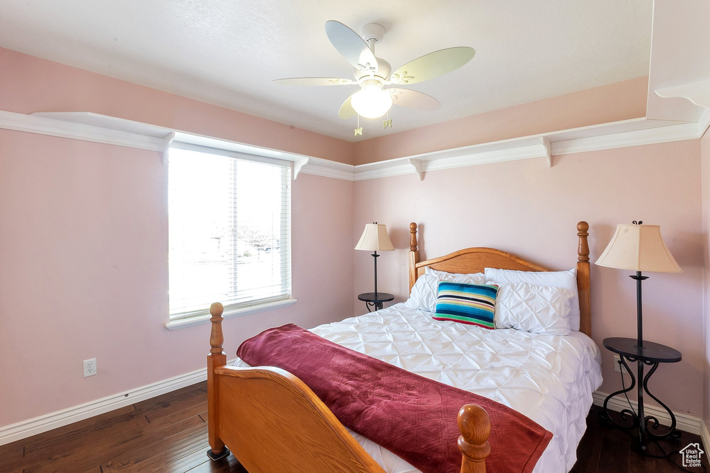 Bedroom with dark hardwood / wood-style flooring, ceiling fan, and ornamental molding