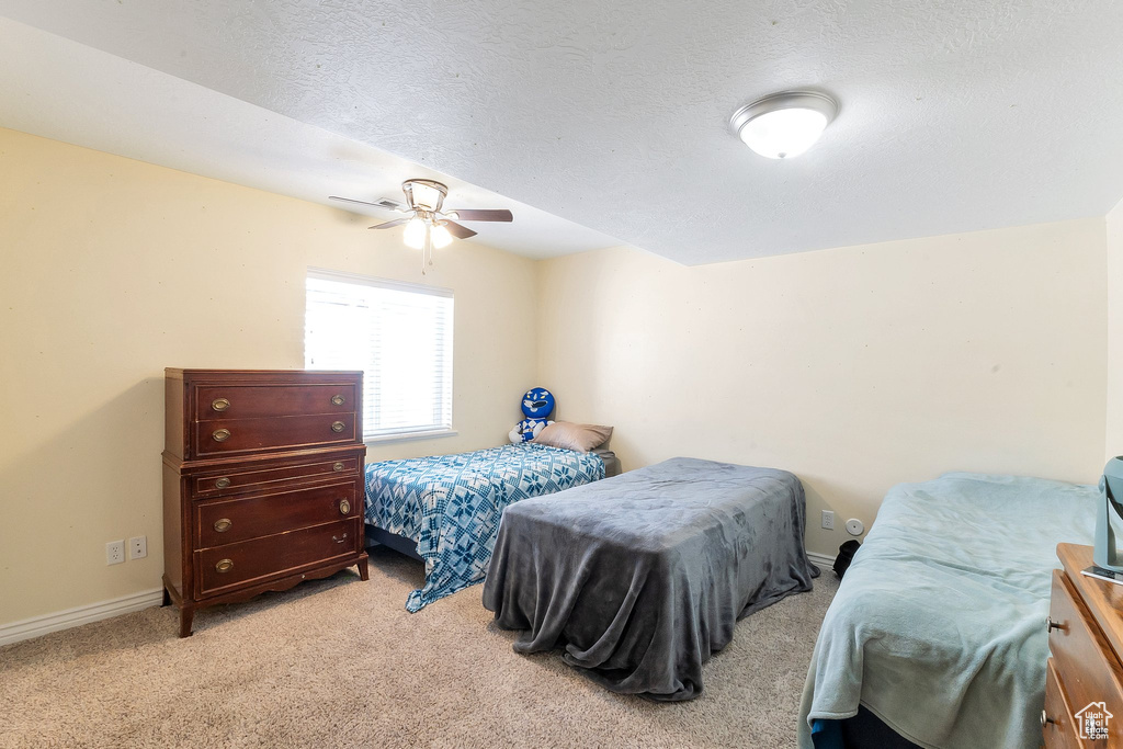 Bedroom with light colored carpet, a textured ceiling, and ceiling fan