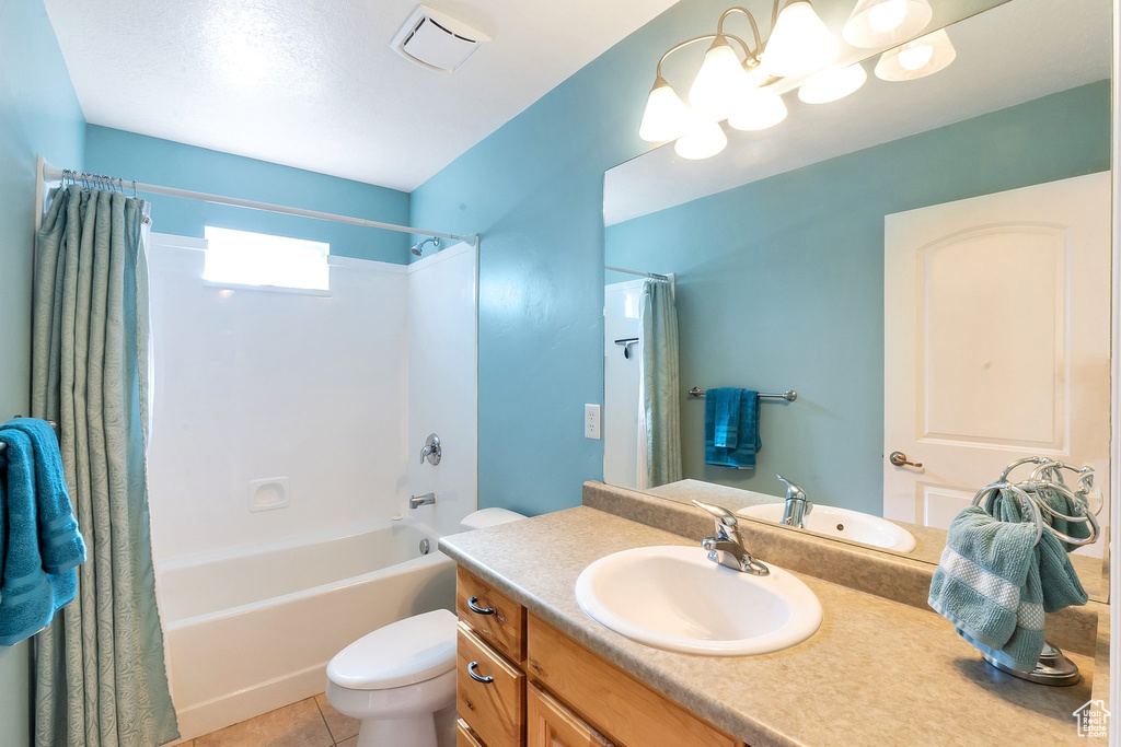 Full bathroom with tile flooring, toilet, large vanity, and shower / tub combo