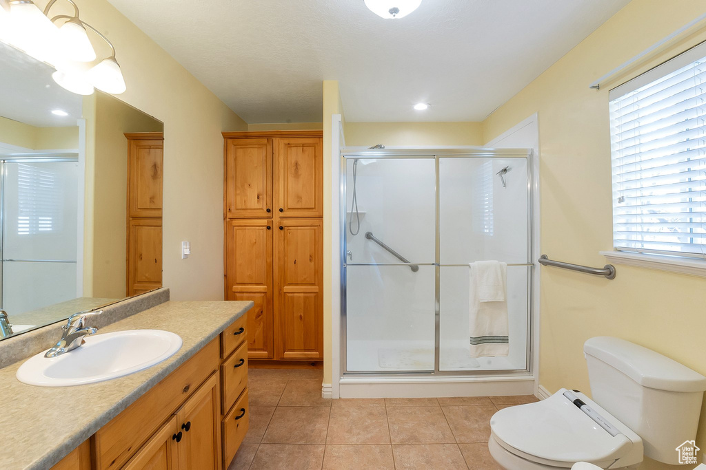 Bathroom featuring toilet, vanity with extensive cabinet space, tile flooring, and plenty of natural light