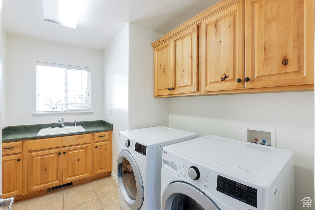 Washroom featuring light tile floors, sink, hookup for a washing machine, cabinets, and washer and clothes dryer