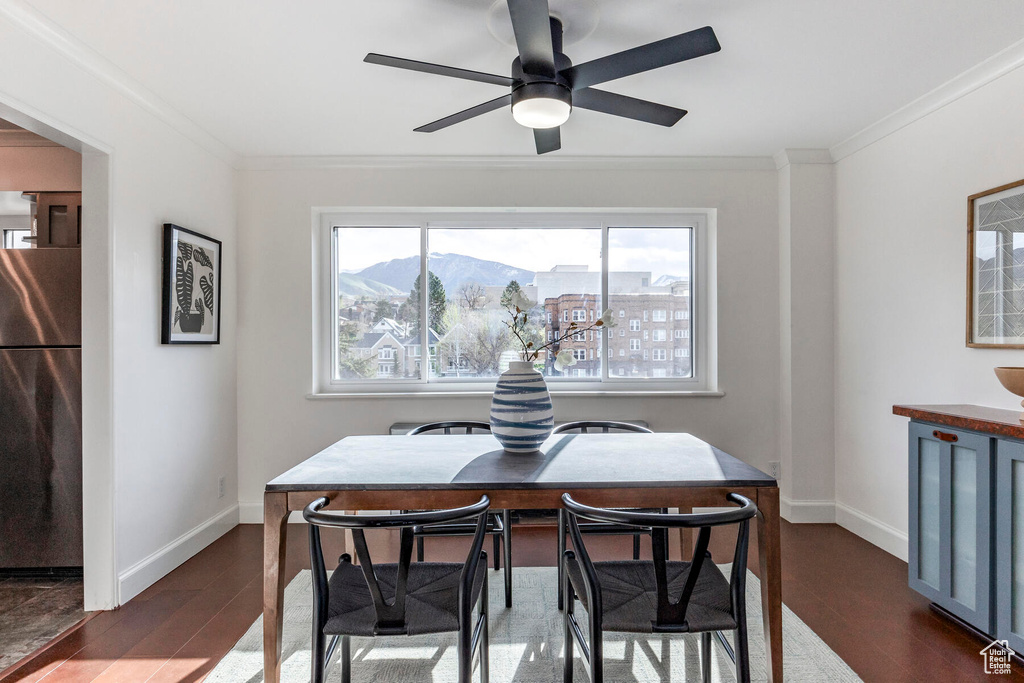 Dining space with a mountain view, ceiling fan, crown molding, and dark wood-type flooring