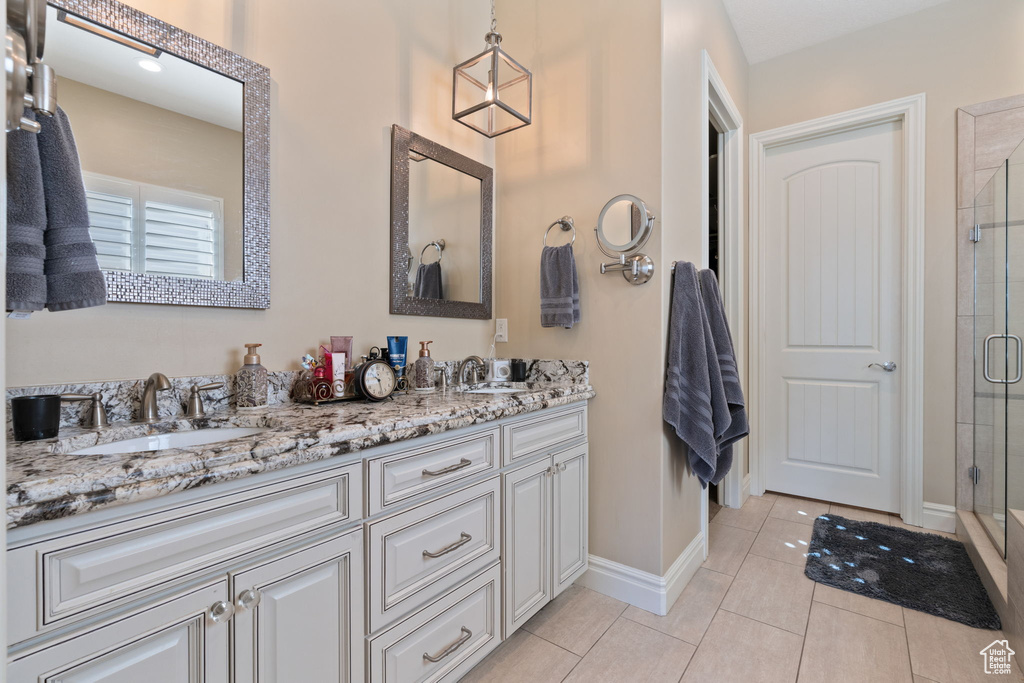 Bathroom featuring dual vanity, tile floors, and a shower with door