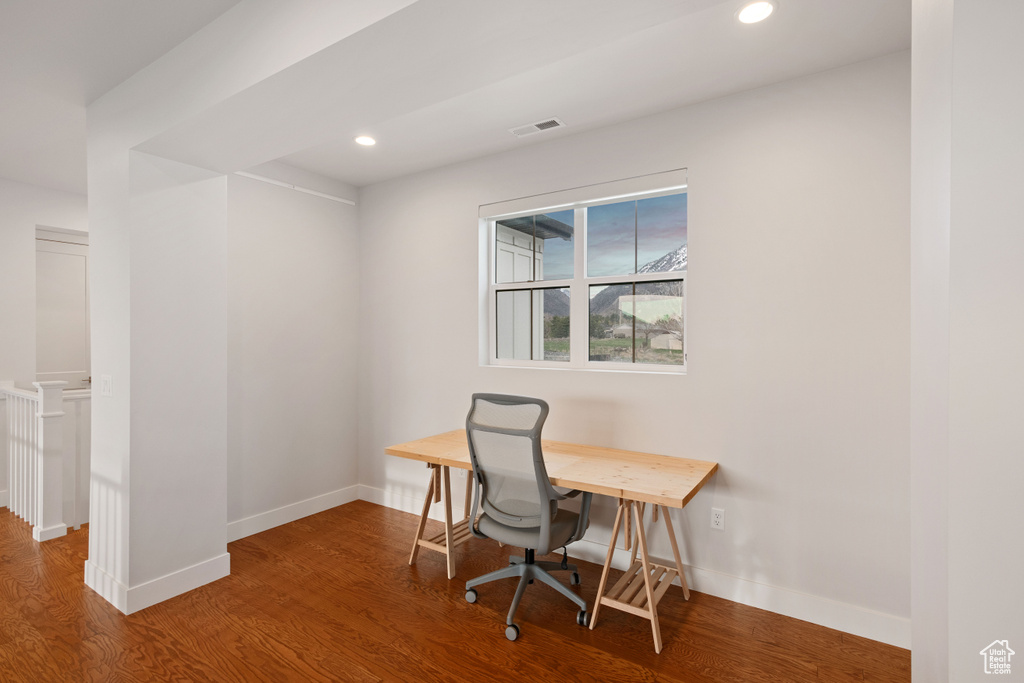 Office space with dark hardwood / wood-style flooring