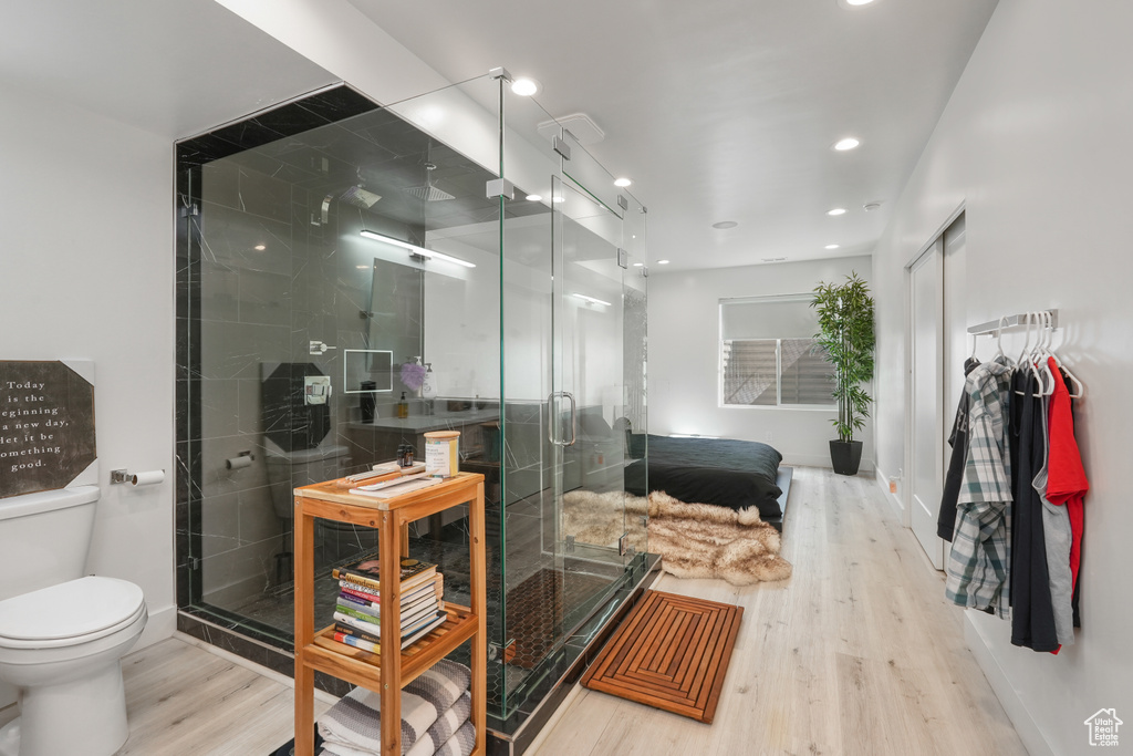 Bathroom featuring walk in shower, tile walls, toilet, and hardwood / wood-style flooring